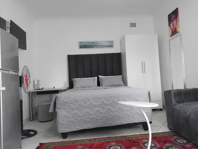 a bedroom with a bed and a table and a couch at Claremont Secured Accommodation in Pretoria