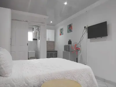a white bedroom with a bed and a television at Claremont Secured Accommodation in Pretoria