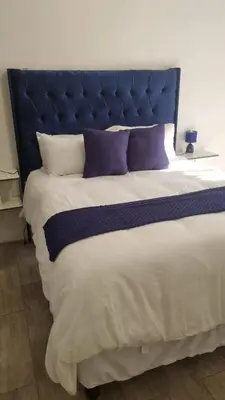 a large bed with a blue headboard and purple pillows at Divine villa in Louis Trichardt