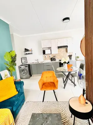 a living room with a blue couch and a kitchen at Classy 1 bed in Midrand at 93 on New Estate in Midrand