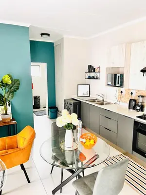 a living room with a glass table and a kitchen at Classy 1 bed in Midrand at 93 on New Estate in Midrand