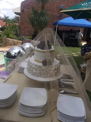 a cake sitting on top of a table with plates at The Palace Guest House in Pretoria