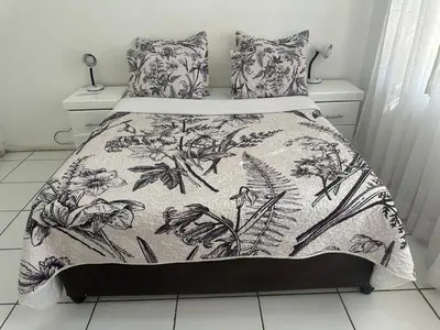 a bed with a black and white comforter and pillows at The Palace Guest House in Pretoria