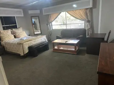 a living room with a couch and a bed and a table at The Palace Guest House in Pretoria