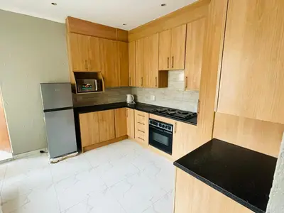 a small kitchen with wooden cabinets and a refrigerator at Cottage tranquility in Pretoria