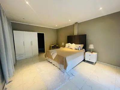 a bedroom with a large bed and a white cabinet at Cottage tranquility in Pretoria