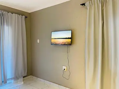 a television on a wall next to a curtain at Cottage tranquility in Pretoria