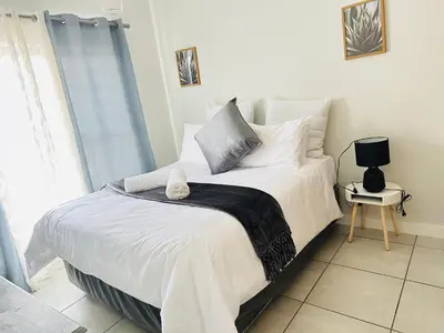 a bedroom with a bed with white sheets and a window at Three bedrooms Apartment at The Blyde Lagoons PTA in Pretoria