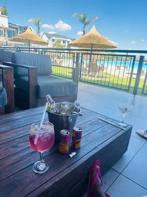 a drink sitting on a wooden table on a patio at Three bedrooms Apartment at The Blyde Lagoons PTA in Pretoria