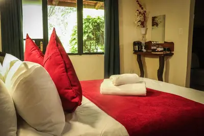 a bedroom with red and white pillows on a bed at The Red Oak Guesthouse in Tzaneen