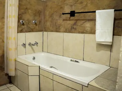 a white bath tub in a bathroom with a shower at The Red Oak Guesthouse in Tzaneen