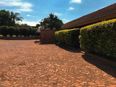 a brick driveway in front of a house with bushes at The Red Oak Guesthouse in Tzaneen