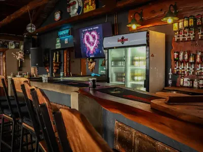 a bar with a television and a counter with chairs at The Red Oak Guesthouse in Tzaneen