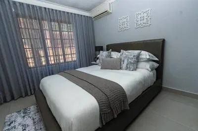 a bedroom with a large bed with pillows at Luxe Living in Nelspruit