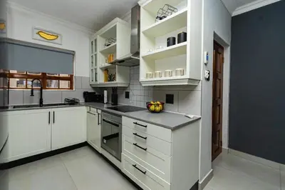 a white kitchen with white cabinets and a sink at Luxe Living in Nelspruit