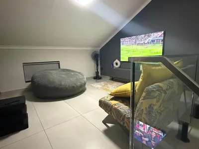 a living room with a couch and a tv at Luxe Living in Nelspruit