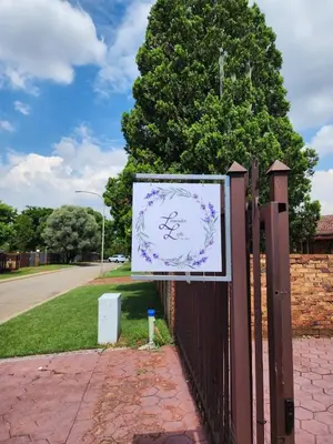 a sign on a fence next to a tree at Lavender Lofts in Centurion