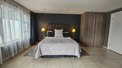 a bedroom with a large bed with two lamps and windows at Belle Vie Boutique Guesthouse in Pretoria