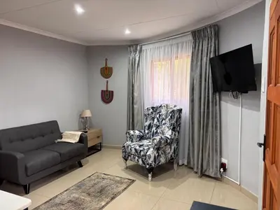 a living room with a couch and a chair at Pazuri Homestay in Kempton Park