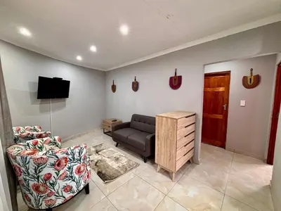 a living room with a couch and a television at Pazuri Homestay in Kempton Park