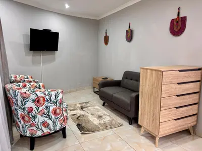 a living room with a couch and a tv and a chair at Pazuri Homestay in Kempton Park