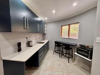 a kitchen with black cabinets and white counter tops at Pazuri Homestay in Kempton Park