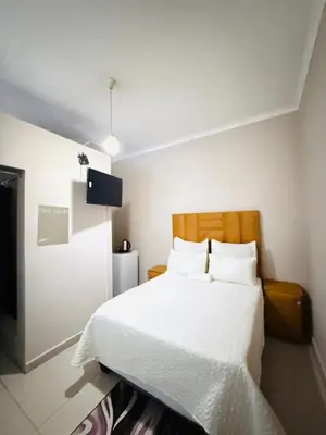 a bedroom with a white bed and a television at Relax Guest House in Ermelo