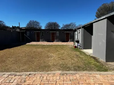 a backyard with a brick driveway and a building at Relax Guest House in Ermelo