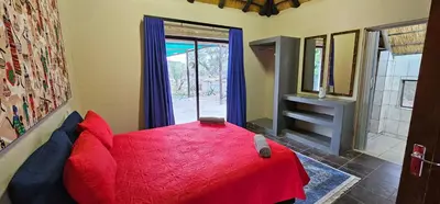 a bedroom with a red bed and a window at The Rondawel in Marloth Park
