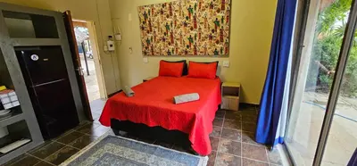 a bedroom with a red bed with a red blanket at The Rondawel in Marloth Park