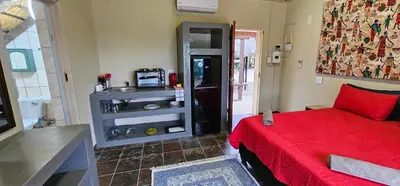 a bedroom with a red bed and a microwave at The Rondawel in Marloth Park