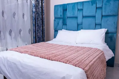 a bedroom with a large bed with a blue headboard at Flora Haven in Polokwane