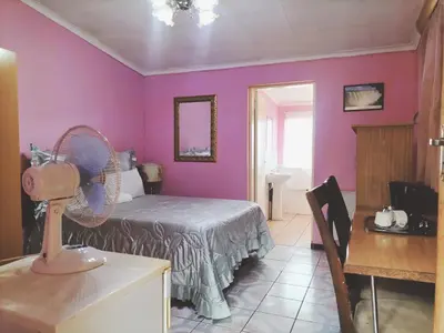 a bedroom with purple walls and a bed with a fan at KILIMANJARO Guest House in Middelburg