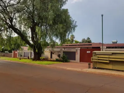 an empty street with a tree and a building at Royal guest lodge in Middelburg