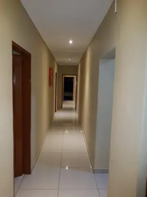 a hallway with a long corridor with a white tile floor at Royal guest lodge in Middelburg