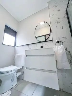 a white bathroom with a toilet and a mirror at Ls apartment in Midrand