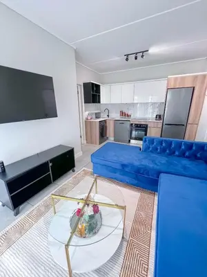 a living room with a blue couch and a table at Ls apartment in Midrand