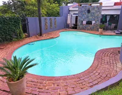 a swimming pool with a brick pathway around it at Mediterranean Palms in Pretoria
