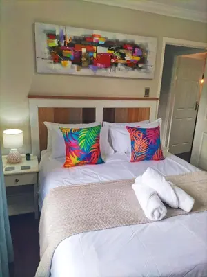 a bedroom with two beds and a painting on the wall at Mediterranean Palms in Pretoria