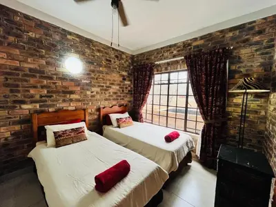 two beds in a room with a brick wall at Akunandaba - A Bush Retreat in Marloth Park