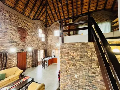 a living room with a brick wall and a staircase at Akunandaba - A Bush Retreat in Marloth Park