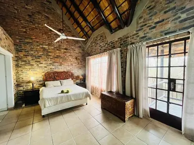 a bedroom with a bed and a brick wall at Akunandaba - A Bush Retreat in Marloth Park