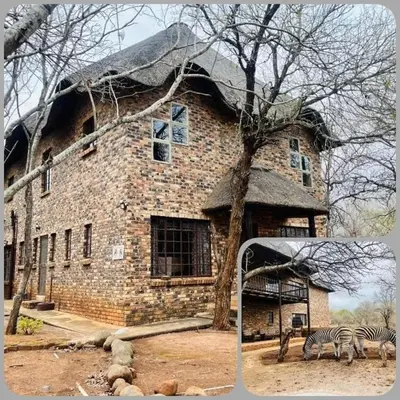 two zebras standing in front of a brick building at Akunandaba - A Bush Retreat in Marloth Park