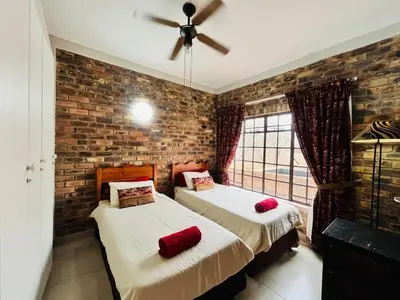 two beds in a room with a brick wall at Akunandaba - A Bush Retreat in Marloth Park