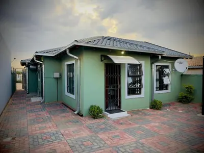a small green house with a brick courtyard in front of it at Khami Guesthouse in Pretoria