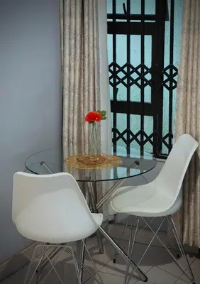 a glass table with two white chairs and a vase with a flower at Khami Guesthouse in Pretoria