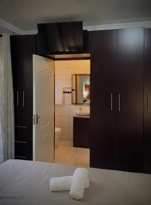 a bedroom with a bed and a bathroom with a sink at Khami Guesthouse in Pretoria