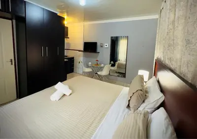 a bedroom with a bed and a living room at Khami Guesthouse in Pretoria