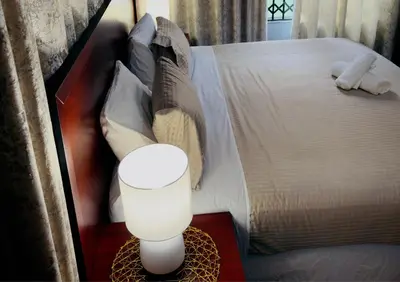 a bedroom with a bed and a lamp on a table at Khami Guesthouse in Pretoria