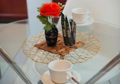 a glass table with two cups and a vase with a red flower at Khami Guesthouse in Pretoria